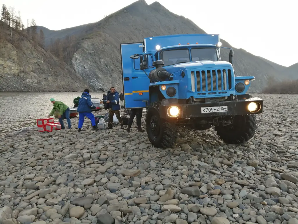 Геологи в Якутии выгружают оборудование и пробы из вахтовки «Урал» у реки для передачи на лодку. Транспортировка по бездорожью и рекам — единственный способ передвижения в арктической зоне.